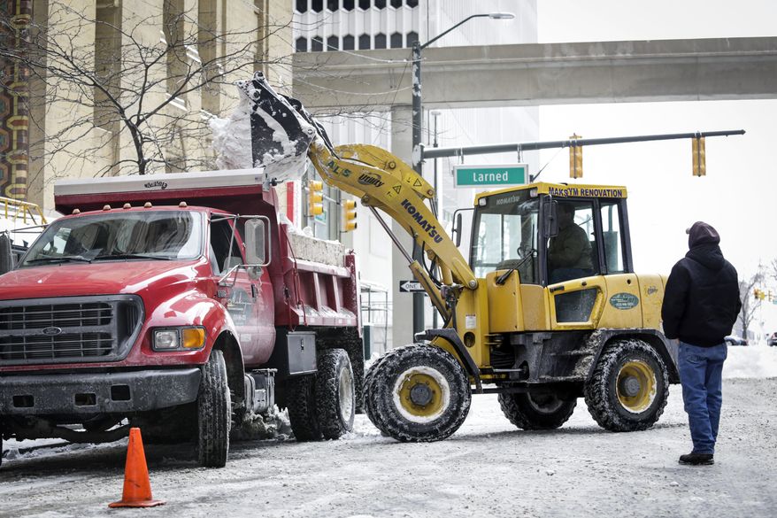Workers from Maksym Renovation and Construction help remove piled up snow on Sunday, March 2, 2014, in Detroit. Slippery streets and highways have caused numerous accidents in Michigan as a fresh wave of snow has fallen on much of Michigan over the weekend. (AP Photo/Detroit Free Press, Jarrad Henderson) DETROIT NEWS OUT; NO SALES; MANDATORY CREDIT