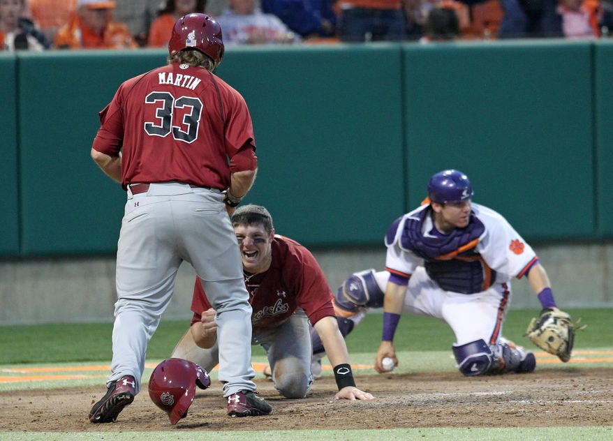 South Carolina's Grayson Greiner, center, celebrates with teammate Kyle Martin after diving around Clemson catcher Chris Okey, right, to score the tying run in an NCAA college baseball game on Sunday, March 2, 2014, in Clemson, S.C. (AP Photo/Anderson Independent-Mail, Mark Crammer) GREENVILLE NEWS OUT; SENECA NEWS OUT