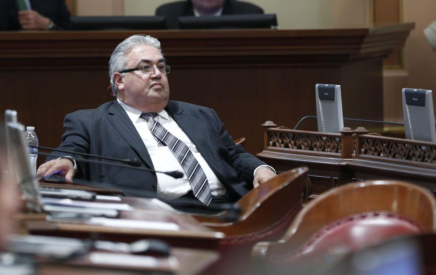 FILE - In this Jan. 6, 2014 file photo, State Sen. Ron Calderon, D-Montebello, sits at his desk during the first Senate session of the new year at the Capitol in Sacramento, Calif. A Senate spokesman said Sunday, March 2, Calderon will take an indefinite leave of absence from the Legislature while he awaits trial. Calderon has been arraigned on charges that he accepted bribes totaling $100,000 in cash and trips, funneling some of the money to his children. (AP Photo/Rich Pedroncelli, File)