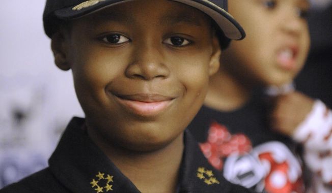 FILE- In a Jan. 31, 2014 file photo, Jayvon Felton, 9, flashes his badge after he was named Chief of Police for a day by Detroit Police Chief James Craig at Detroit Public Safety Headquarters in Detroit. Felton, 9, diagnosed with leukemia, died Feb. 24 at a Detroit hospital. Dozens of police officers were among those who gathered Monday, March 3, 2014 for funeral for the fourth-grader who had always wanted to be a Detroit police officer.  (AP Photo/Detroit News, David Coates, File)