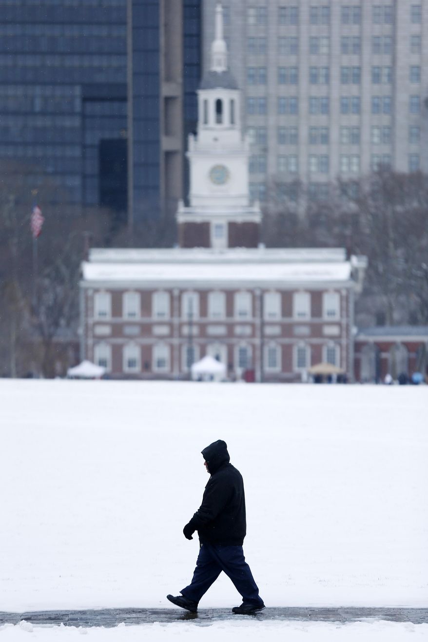 A man walks past Independence Hall after a winter snowstorm Monday, March 3, 2014, in Philadelphia. Spring is in sight, but winter kept its icy hold on much of the country Monday, with up to a foot of snow and plummeting temperatures expected across the Mid-Atlantic states and up the East Coast. (AP Photo/Matt Rourke)