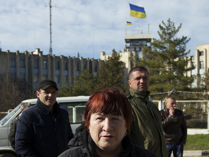 Local residents gather outside the Ukrainian naval base headquarters in the town of Novo-Ozerne, some 90 km west of the Crimean capital Simferopol, Ukraine, on Monday March 3, 2014. For years, the little Crimean town was closed off from the rest of the world, a secretive community, at the edge of a key Soviet naval base, sealed by roadblocks and armed guards. There’s not much in town anymore. But the Russians want it. And the little forgotten town is now sharply divided, torn between those who welcomed the arrival here over the weekend of dozens of Russian soldiers wearing unmarked uniforms, and those who back the Ukrainians who are refusing to surrender their weapons. (AP Photo/Ivan Sekretarev)
