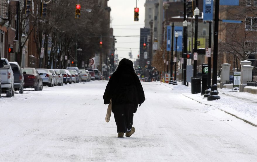 A pedestrian walks in the middle of a snow covered street, Monday, March 3, 2014, in downtown Cincinnati. The area received from three to six inches of new snow. (AP Photo/Al Behrman)