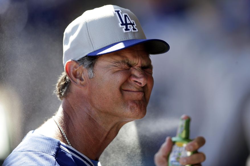 Los Angeles Dodgers manager Don Mattingly sprays on suntan lotion in the dugout before the Dodgers play the Oakland Athletics in a spring training baseball game Monday, March 3, 2014, in Phoenix. (AP Photo/Gregory Bull)