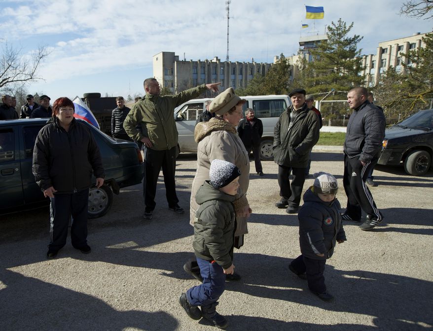 Local residents, some of them pro-Russian supporters, gather outside the Ukrainian naval base headquarters in the town of Novo-Ozerne, some 90 km west of the Crimean capital Simferopol, Ukraine, on Monday March 3, 2014. For years, the little Crimean town was closed off from the rest of the world, a secretive community, at the edge of a key Soviet naval base, sealed by roadblocks and armed guards. There’s not much in town anymore. But the Russians want it. And the little forgotten town is now sharply divided, torn between those who welcomed the arrival here over the weekend of dozens of Russian soldiers wearing unmarked uniforms, and those who back the Ukrainians who are refusing to surrender their weapons. (AP Photo/Ivan Sekretarev)
