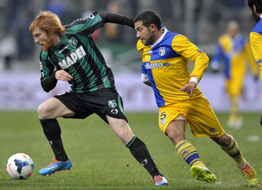 Sassuolo's Davide Biondini, left, vies for the ball with Parma's Walter Gargano of Uruguay, during their Serie A soccer match at Reggio Emilia's Mapei stadium, Italy, Sunday, March 2, 2014. (AP Photo/Marco Vasini)