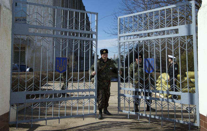 A Ukrainian soldier closes the naval base headquarter gate in the town of Novo-Ozerne, some 90 km west of the Crimean capital Simferopol, Ukraine, on Monday March 3, 2014. For years, the little Crimean town was closed off from the rest of the world, a secretive community, at the edge of a key Soviet naval base, sealed by roadblocks and armed guards. There’s not much in town anymore. But the Russians want it. And the little forgotten town is now sharply divided, torn between those who welcomed the arrival here over the weekend of dozens of Russian soldiers wearing unmarked uniforms, and those who back the Ukrainians who are refusing to surrender their weapons. (AP Photo/Ivan Sekretarev)