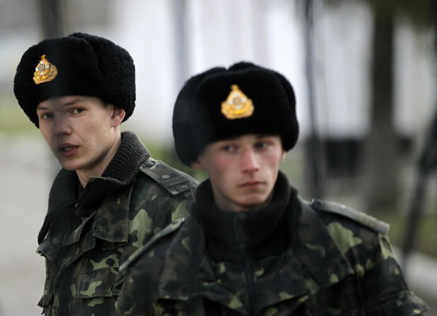 Ukrainian soldiers guard the gate of Ukraine's infantry base in Perevalne, Ukraine, Sunday, March 2, 2014. Hundreds of armed men in trucks and armored vehicles surrounded a Ukrainian military base Sunday in Crimea, blocking its soldiers from leaving. The outnumbered Ukrainians placed a tank at the base's gate, leaving the two sides in a tense standoff. (AP Photo/Darko Vojinovic)