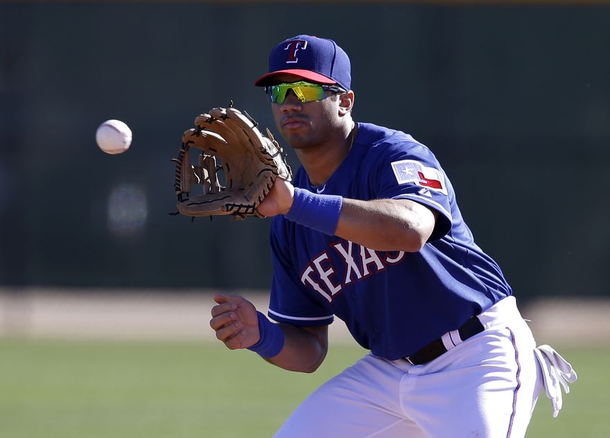 Seattle Seahawks quarterback Russell Wilson reaches up to grab a throw as he works out with the Texas Rangers during spring training baseball practice, Monday, March 3, 2014, in Surprise, Ariz. (AP Photo/Tony Gutierrez)