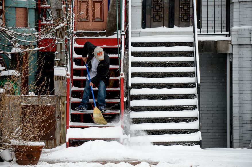 JosŽ Rosado sweeps snow from the stairs of Thai X-ing in Shaw as the region gets 6-8 inches of snow, Washington, D.C., Monday, March 3, 2014. (Andrew Harnik/The Washington Times)