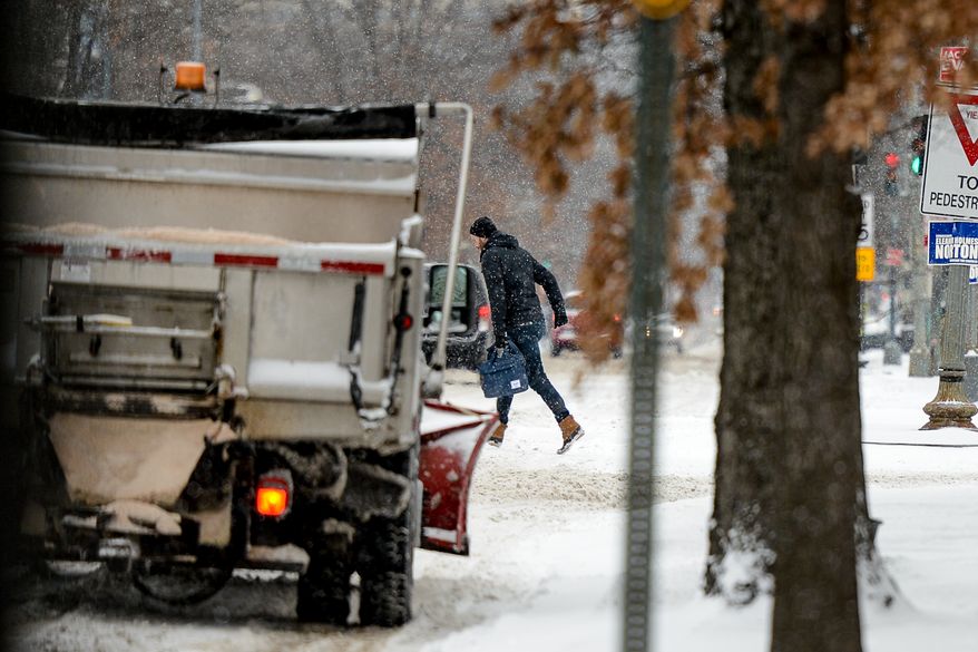 A pedestrian runs across the street in Shaw as the region gets 6-8 inches of snow, Washington, D.C., Monday, March 3, 2014. (Andrew Harnik/The Washington Times)