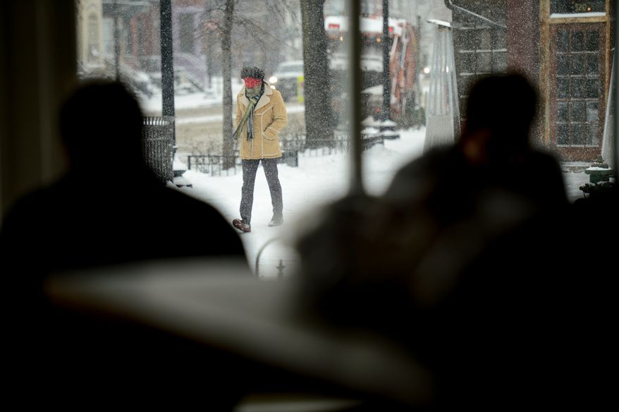 Pedestrians walk through the snow and coffee drinkers relax at Bistro Bohem as the region gets 6-8 inches of snow, Washington, D.C., Monday, March 3, 2014. (Andrew Harnik/The Washington Times)