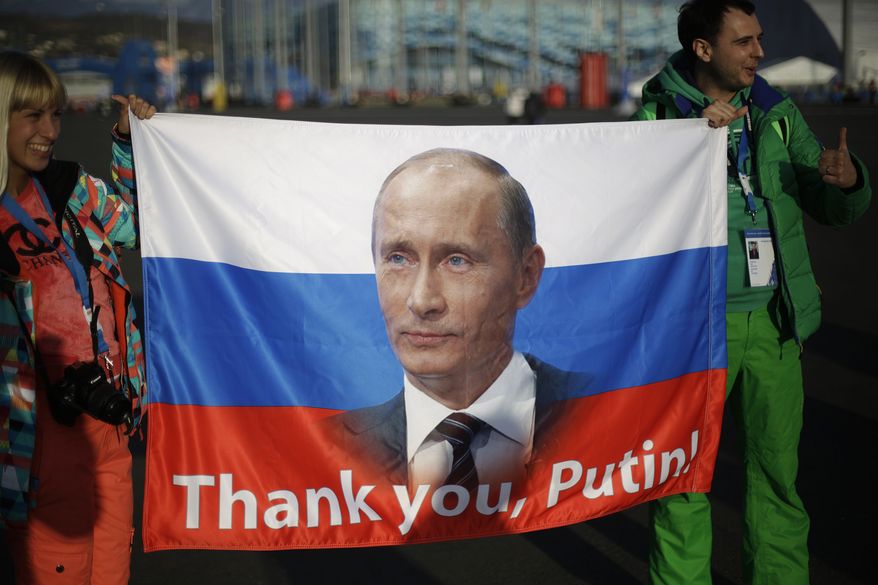 Veleriya Obarevich, left, and Yan Shamilov carry a Russian flag with the message "Thank you, Putin!" written across it through the Olympic Park ahead of the 2014 Winter Olympics closing ceremony, Sunday, Feb. 23, 2014, in Sochi, Russia. (AP Photo/David Goldman)