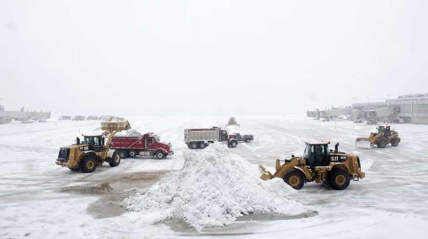 Workers clear the tarmac of snow so that flights can resume at Washington's Ronald Reagan National Airport, Monday, March 3, 2014. The National Weather Service has issued a Winter Storm Warning for the greater Washington Metropolitan region, prompting area schools and the federal government to close for the wintry weather. (AP Photo/Cliff Owen)