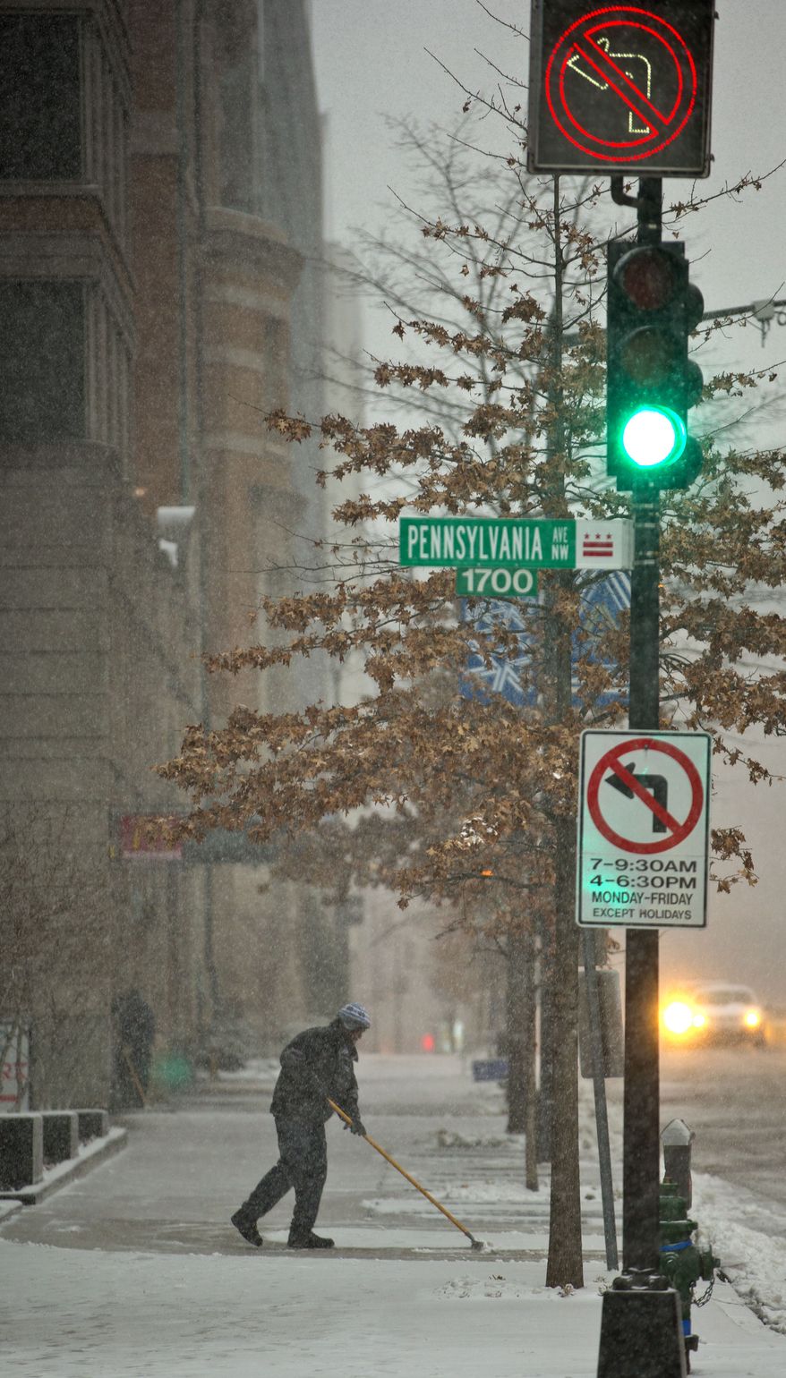 A worker clears the sidewalk of snow along 17th Street NW in downtown Washington, Monday, March 3, 2014. The National Weather Service has issued a Winter Storm Warning for the greater Washington Metropolitan region, prompting area schools and the federal government to close for the wintry weather. (AP Photo/Pablo Martinez Monsivais)
