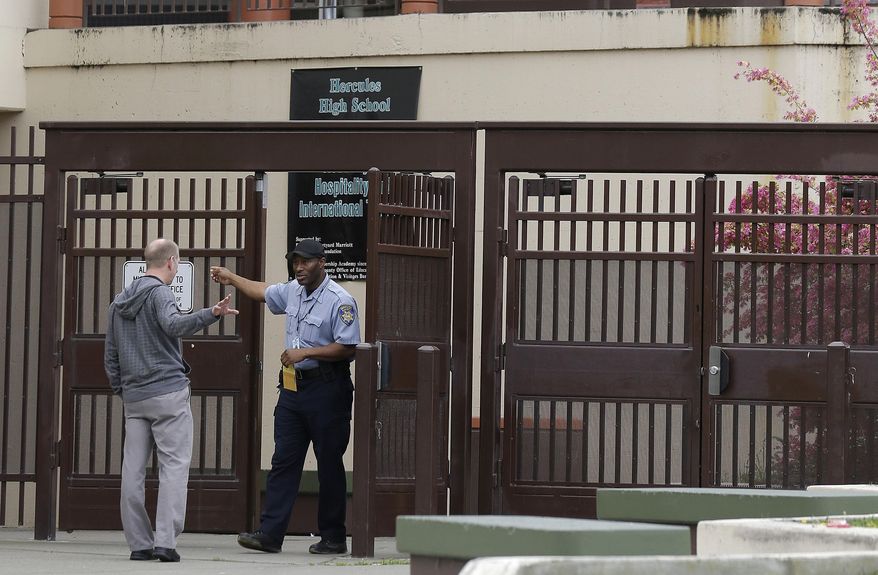 A security guard talks to man at the gate outside of the Hercules Middle/High School campus in Hercules, Calif., Tuesday, March 4, 2014. Police on Tuesday were investigating reports of a brutal assault of a transgender teen. The 15-year-old student told officers that he was leaving a boy's bathroom at the school on Monday when three teenage boys pushed him inside a handicapped stall and physically and sexually assaulted him, Hercules police Detective Connie Van Putten said. (AP Photo/Jeff Chiu)