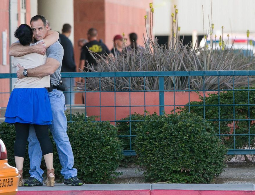 A man and woman embrace as people react to an update at St. Joseph's Hospital on Monday, March 3, 2014, in Phoenix, about the police-involved shooting that took place Monday afternoon in Phoenix. A Phoenix police officer died and another was in critical condition after a shootout Monday that also killed a man wanted on a felony warrant, authorities said. (AP Photo/The Arizona Republic, Michael Schennum)