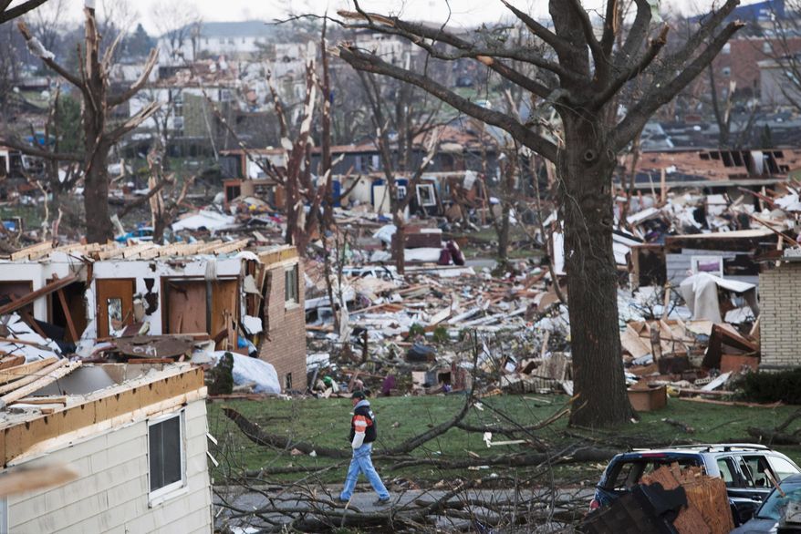 FILE - In this Nov. 18, 2013 file photo, a man walks through what is left of a neighborhood in Washington, Ill., a day after a tornado ripped through the central Illinois town. Tornado sirens were tested Tuesday, March 4, 2014, in Washington for the first time since since twisters crossed the state in November, killing seven people and destroying hundreds of homes. The tornado that hit Washington had winds that reached up to 190 mph. It was on the ground for more than 46 miles. (AP Photo/Armando Sanchez, File)
