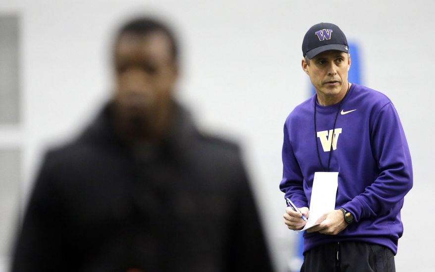 New Washington head football coach Chris Petersen, right, takes notes on the first day of spring NCAA college football practice, Tuesday, March 4, 2014, in Seattle. (AP Photo/Ted S. Warren)