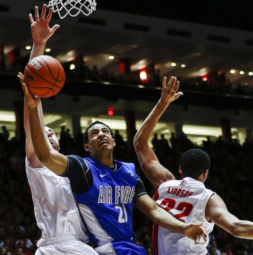 Air Force's DeLovell Earls (21) powers his way to a basket during the first half guarded by New Mexico's Alex Kirk (53) and Merv Lindsay (22) of an NCAA college basketball game at The Pit in Albuquerque, N.M., Wednesday, March 5, 2014. (AP Photo/Juan Antonio Labreche)
