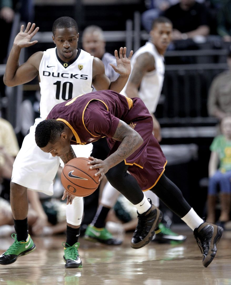 Arizona State guard Jahii Carson, right, loses his balance driving against Oregon guard Johnathan Loyd during the first half of an NCAA college basketball game in Eugene, Ore., Tuesday, March 4, 2014. (AP Photo/Don Ryan)