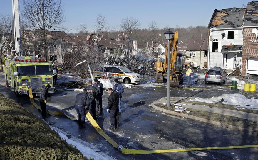 Firefighters move a hose near the debris of the previous day's explosion at a townhouse complex in Ewing, N.J. on Wednesday, March, 5, 2014. Investigators are looking to determine what triggered a natural gas leak and explosion that devastated the development, killing one woman and injuring seven workers. (AP Photo/Mel Evans)