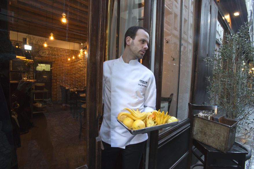 Chef Greg Marchand holds a tray of vegetables in the doorway of his restaurant Frenchie in Paris on Thursday, Feb. 13, 2014. "A lot of young chefs - I'm part of it - open a restaurant with no investor, so with not much money. It's often small places, with no designer work because they cannot afford it. But what we have is a craft, knowledge, experience," he said. (AP Photo/Michel Euler)
