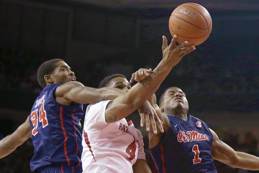 Mississippi's Aaron Jones (34) and Martavious Newby (1) try to block a shot by Arkansas' Coty Clarke (4) in the first half of an NCAA college basketball game in Fayetteville, Ark., Wednesday, March 5, 2014. (AP Photo/Danny Johnston)