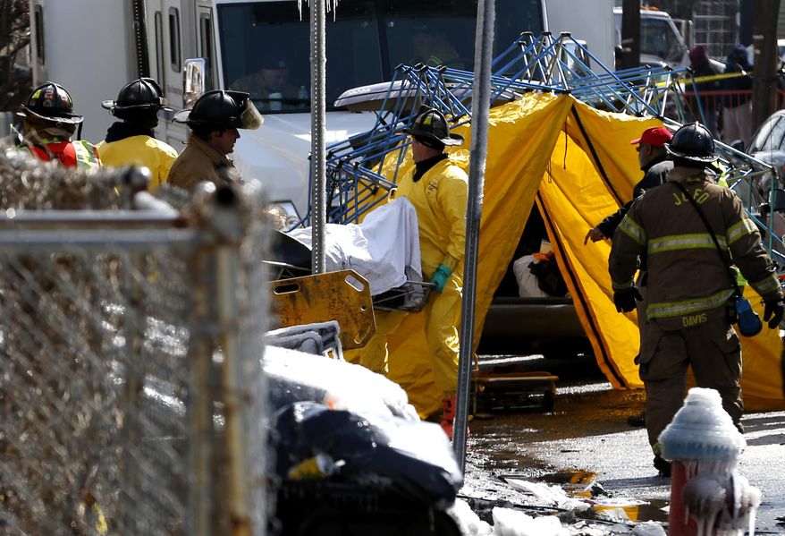Officials carry a body out of the charred remains of a home where a fire broke out early in the morning on Thursday, March 6, 2014, in Jersey City, N.J. Authorities have recovered two bodies and are searching for two people who are missing at the scene the a four-alarm fire. Mayor Steven Fulop said a couple in their 80s and their two sons, who are in their 50s, were unaccounted for after the blaze on Grant Avenue was extinguished early Thursday. Authorities have not identified the two bodies that were found in the charred home. (AP Photo/Julio Cortez)
