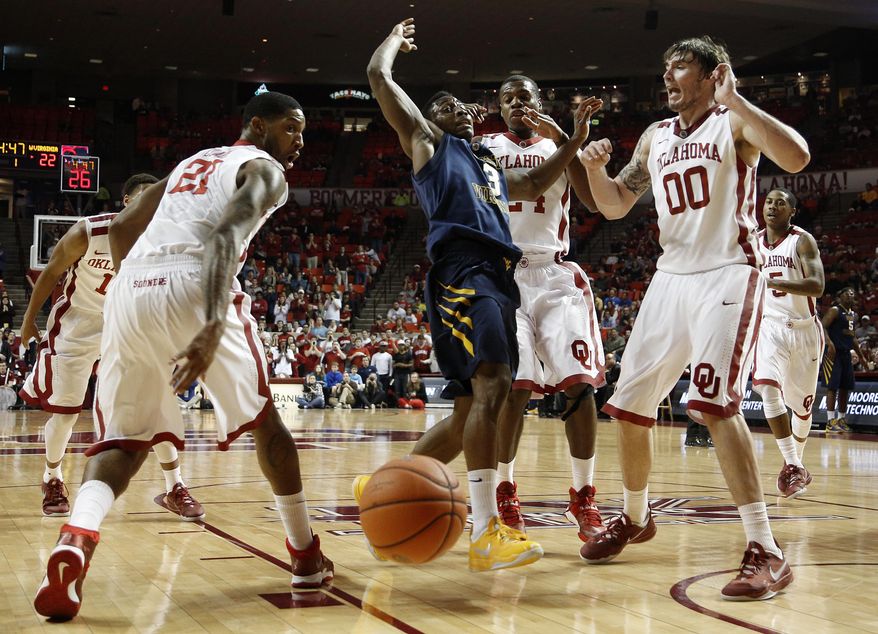 Oklahoma's Cameron Clark (21), Buddy Hield (24), and Ryan Spangler (00), fight for a rebound with West Virginia's Juwan Staten (3) during an NCAA college basketball game in Norman, Okla., Wednesday, March 5, 2014. (AP Photo/Garett Fisbeck)