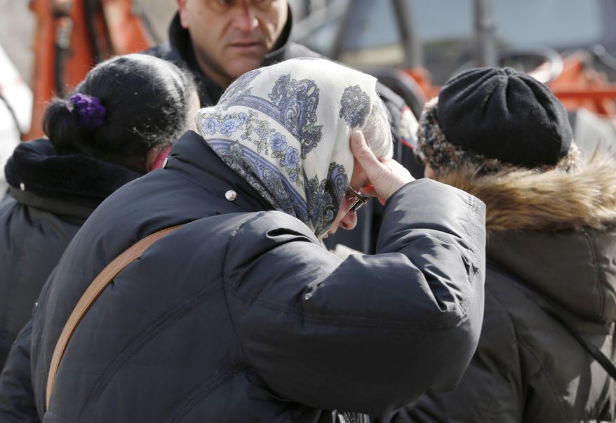 A woman reacts near the scene of a four-alarm fire in Jersey City, N.J. on Thursday, March 6, 2014. Mayor Steven Fulop said a couple in their 80s and their two sons, who are in their 50s, were unaccounted for after the blaze on Grant Avenue was extinguished early Thursday. Authorities have not identified the two bodies that were found in the charred home. (AP Photo/Julio Cortez)