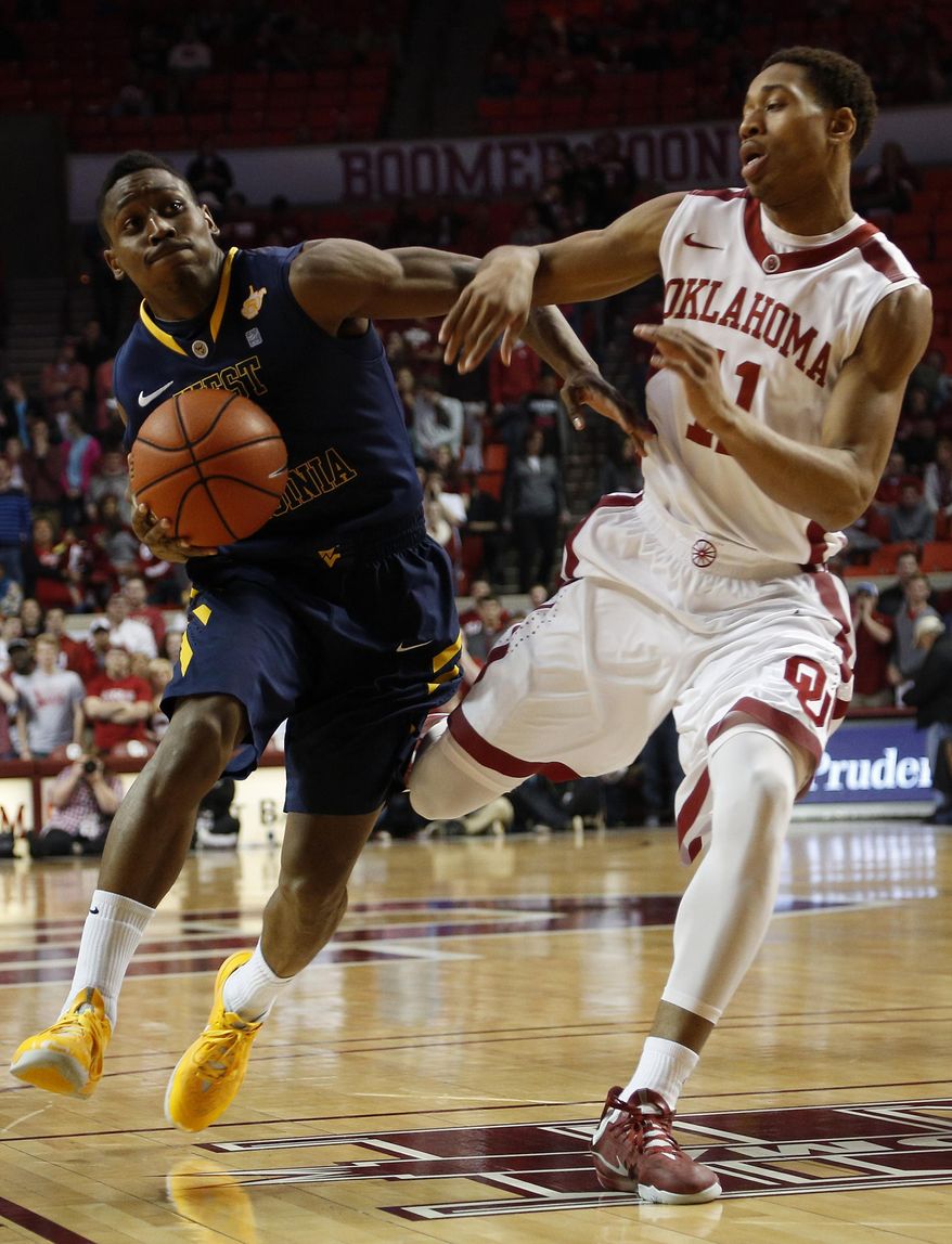 West Virginia's Juwan Staten (3) drives the ball past Oklahoma's Isaiah Cousins (11) during an NCAA game between Oklahoma and West Virginia at the Lloyd Noble Center in Norman, Okla., Wednesday, March 5, 2014. (AP Photo/Garett Fisbeck)