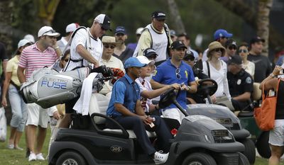 Tiger Woods, center, gets a ride in a cart with his caddy Joe LaCava, left, after play was suspended due to approaching inclement weather during the first round of the Cadillac Championship golf tournament, Thursday, March 6, 2014, in Doral, Fla. (AP Photo/Lynne Sladky)
