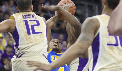 UCLA&#39;s Norman Powell, center, shoots as he falls to floor while Washington&#39;s Andrew Andrews (12) and Desmond Simmons defend in the first half of an NCAA college basketball game on Thursday, March 6, 2014, in Seattle. (AP Photo/Stephen Brashear)