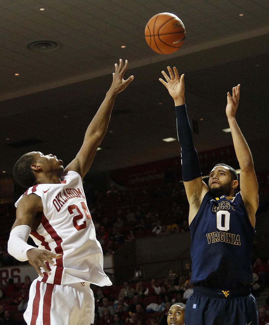 West Virginia's Rémi Dibo (0) takes a shot over Oklahoma's Buddy Hield (24) during an NCAA game between Oklahoma and West Virginia at the Lloyd Noble Center in Norman, Okla., Wednesday, March 5, 2014. (AP Photo/Garett Fisbeck)