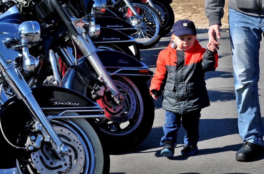 James Michael Gisonna, 2, holds his dad James Gisonna's hand while looking over the bikes at the Freedom Biker Church Sunday, Feb. 16, 2014. (AP Photo/The Fayetteville Observer, Cindy Burnham.)