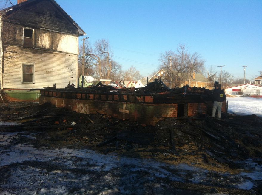 Two investigators with the U.S. Bureau of Alcohol, Tobacco, Firearms and Explosives look over the remnants of a house destroyed by fire in Detroit on Friday, March 7, 2014. The home, known as the "Party Animal" house or "Doll House," was part of the Heidelberg Project interactive outdoor art installation that has been the target of at least eight suspicious fires since May. (AP Photo, Mike Householder)