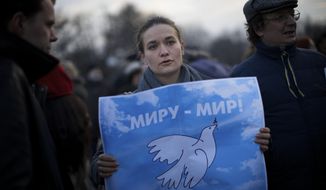 An anti-war demonstrators gather holds a poster reading &amp;quot;Peace to the World!&amp;quot; during a rally in Moscow, Russia, late Friday, March 7, 2014. Russia rallied support Friday for a Crimean bid to secede from Ukraine, with a leader of Russia’s parliament assuring her Crimean counterpart that the region would be welcomed as “an absolutely equal subject of the Russian Federation.” Across Red Square, 65,000 people waved Russian flags, chanting “Crimea is Russia!”(AP Photo/Alexander Zemlianichenko)
