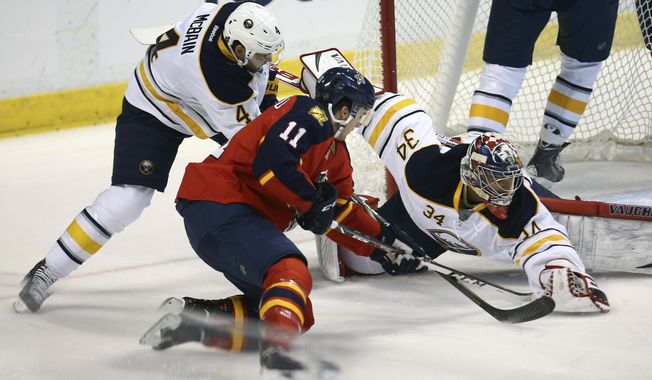 Florida Panthers&#x27; Jonathan Huberdeau (11) tries to score as Buffalo Sabres goalie Michael Neuvirth (34) and Jamie McBain (4) try to block the shot during the first period of an NHL hockey game in Sunrise, Fla., Friday, March 7, 2014. (AP Photo/J Pat Carter)