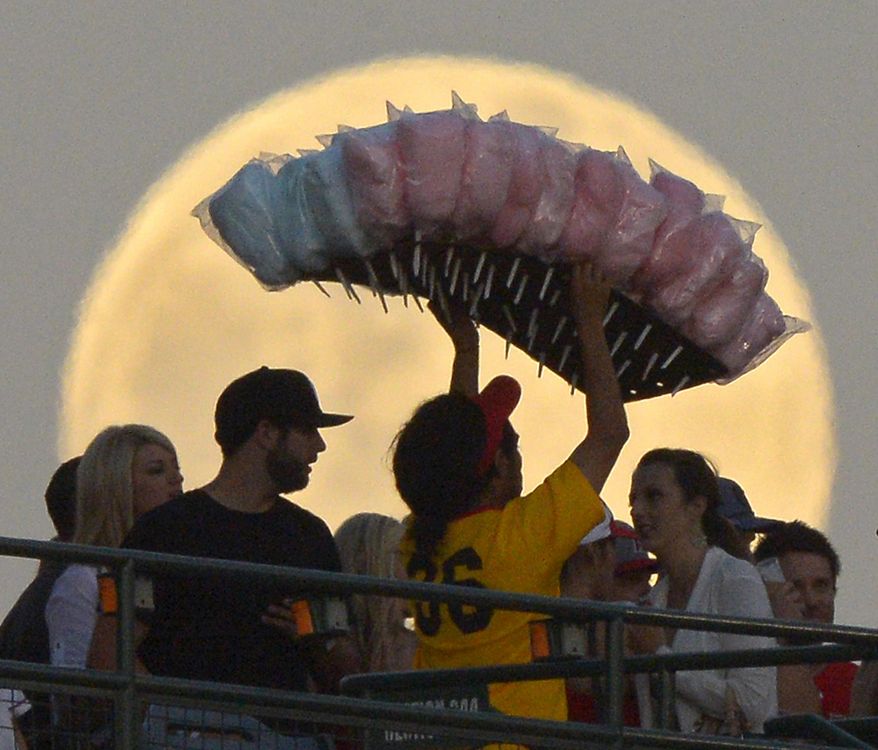 FILE - In this June 22, 2013 file photo, a cotton candy vendor walks in front of a full moon during the Los Angeles Angels' baseball game against the Pittsburgh Pirates, in Anaheim, Calif. The photo was part of a series of images by photographer Mark J. Terrill which won the Thomas V. diLustro best portfolio award for 2013 given out by the Associated Press Sports Editors during their annual winter meeting in Indianapolis. (AP Photo/Mark J. Terrill, File)