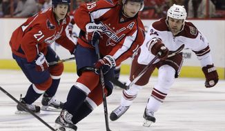 Washington Capitals center Nicklas Backstrom (19), and Phoenix Coyotes center Kyle Chipchura (24) skate for the puck during the first period of an NHL hockey game, Saturday, March 8, 2014, in Washington. At left is Capitals center Brooks Laich. (AP Photo/Carolyn Kaster)