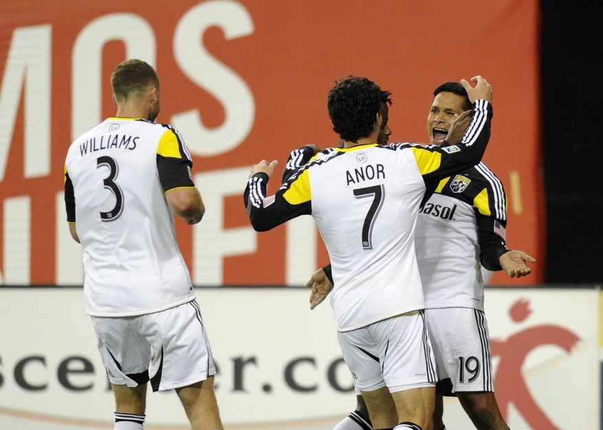 Columbus Crew's Jairo Arrieta (19) celebrates his goal with Bernardo Anor (7) and Josh Williams (3) during the first half of an MLS soccer game against D.C. United, Saturday, March 8, 2014, in Washington. (AP Photo/Nick Wass)