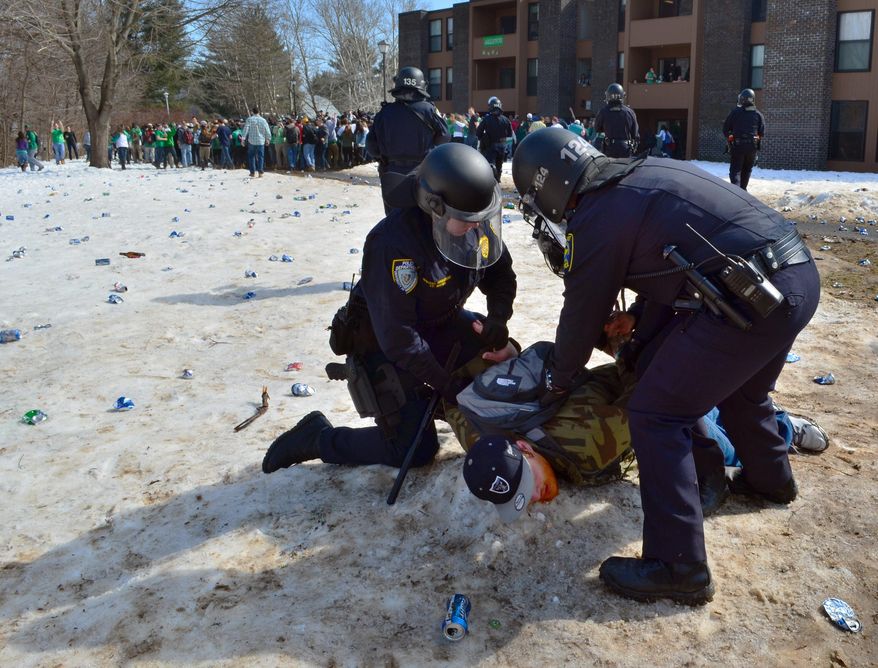 Police detain a participant in the pre-St. Patrick's Day "Blarney Blowout" near the University of Massachusetts in Amherst, Mass. on Saturday, March 8, 2014. According to the Amherst police department, four police officers were hurt as they worked to disperse hundreds of unruly students who were throwing beer cans and bottles at police on Saturday as large crowds gathered at the off-campus apartment complex. Police in riot gear arrested 35 at the event. (AP Photo/The Republican, Robert Rizzuto)
