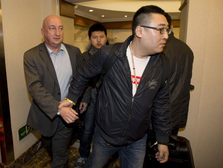 Hugh Dunleavy, left, from commercial director of the Malaysia Airlines is escorted by an unidentified Chinese man after speaking for relatives or friends of passengers aboard the missing plane, in Beijing Sunday, March 9, 2014. An international fleet of planes and ships scouted the waters between Malaysia and Vietnam for any clues to the fate of the Malaysian Airlines Boeing 777, which disappeared less than an hour after taking off from Kuala Lumpur bound for Beijing on Saturday, March 8. (AP Photo/Andy Wong)