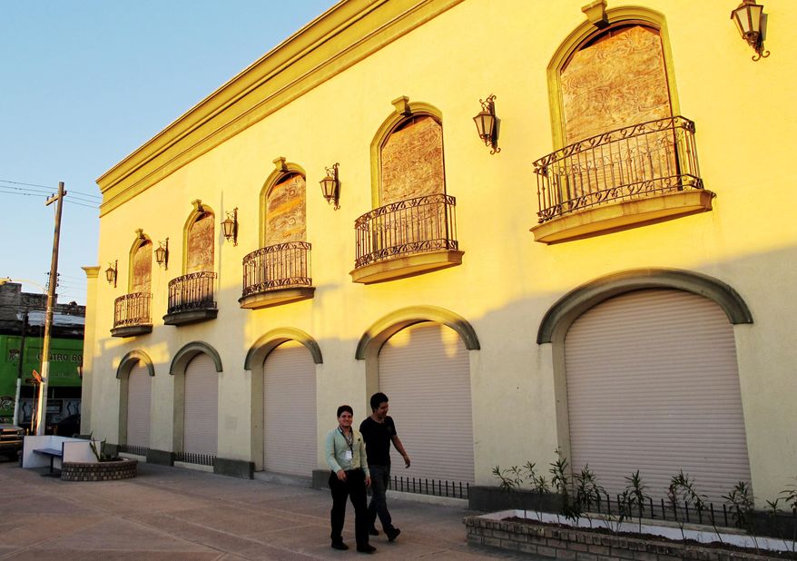 Two men walk by a boarded up souvenir shop in Matamoros, Mexico, Friday, Feb. 28, 2014. In the midst of a three-year increase in American tourism in Mexico, communities along the Rio Grande are trying to win back U.S. tourists and revitalize their tourism industry. (AP Photo/Olga Rodriguez)