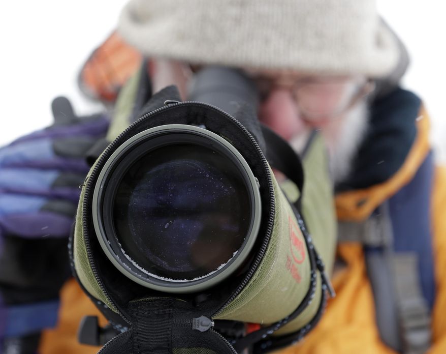 Birding enthusiast Ian Worley of Cornwall, Vt., uses a scope to watch ducks on Lake Champlain on Wednesday, March 5, 2014, in Essex, N.Y. Lake Champlain is frozen solid, except for two stretches of open water where two ferries carry passengers between Vermont and New York. The only open water within miles is attracting thousands of ducks and bald eagles looking to eat the ducks. It is had the side benefit of attracting birders from far away looking to spot rare duck species. (AP Photo/Mike Groll)