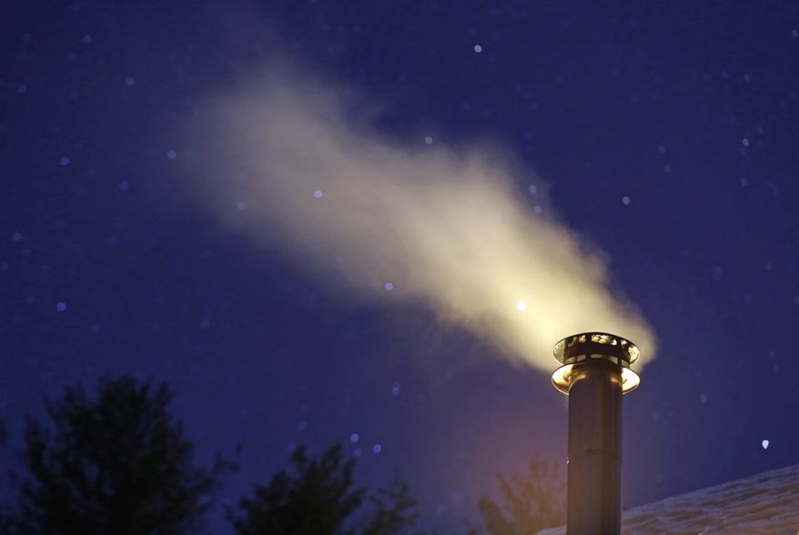 Smoke from a wood stove wafts into the night sky, Saturday, March 8, 2014 in Freeport, Maine. Proposed regulations from the U.S. Environmental Protection Agency would significantly reduce the amount of particle pollution allowed from the smokestacks of new residential wood-powered heaters. (AP Photo/Robert F. Bukaty)