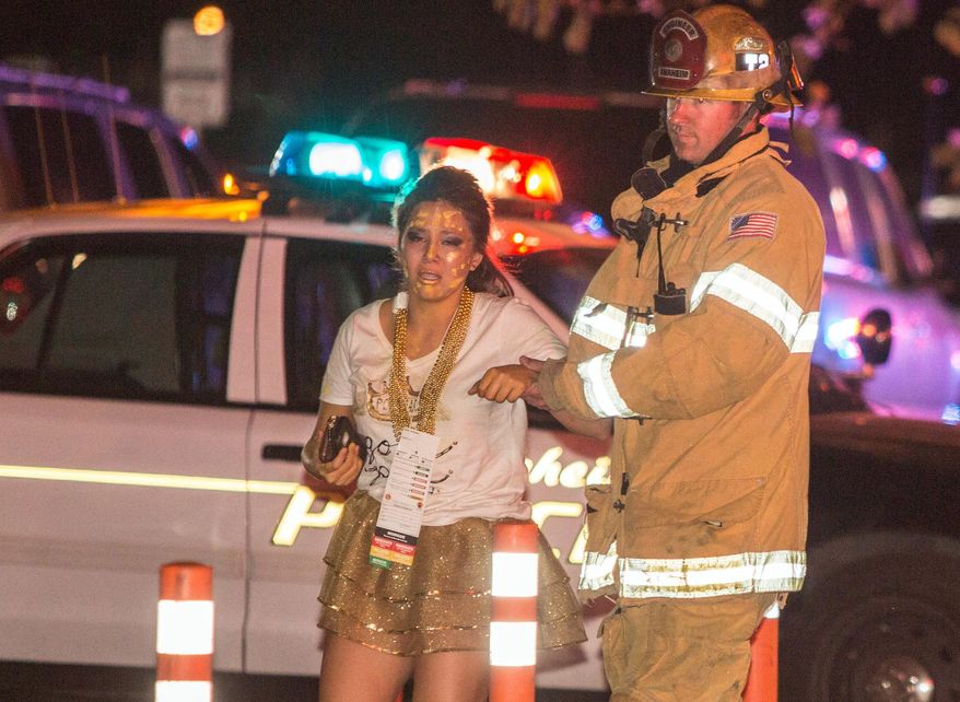 A firefighter assists an injured student after a stage collapsed during a student event at Servite High School in Anaheim, Calif., Saturday, March 8, 2014. Authorities said 30-40 people were taken to hospitals with mainly minor injuries. (AP Photo/Kevin Warn)