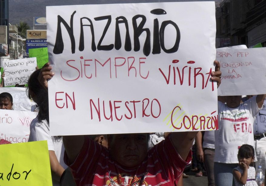 FILE - In this Dec. 12, 2010 file photo, a man holds a sign that reads in Spanish "Nazario will always live in our hearts," referring to La Familia drug cartel leader Nazario Moreno Gonzalez during a demonstration after the government announced he was killed in Apatzingan, Mexico. Years later on Sunday, March 9, 2014, officials say they are trying to determine if a man killed in an early morning shootout is Moreno. Some residents of Michoacan have reported seeing Moreno as his former cartel, La Familia Michoacana, was morphing into the more vicious and powerful Knights Templar. (AP Photo/Primera Plana, File)