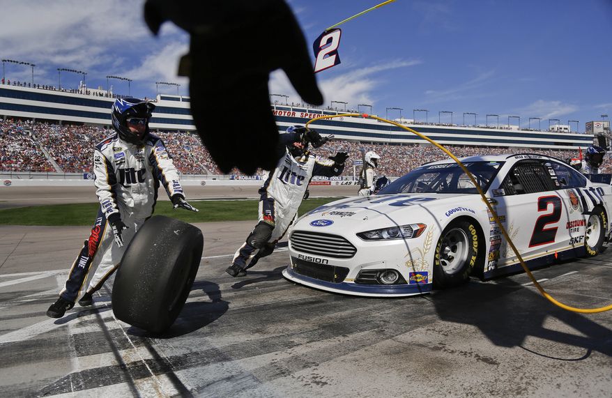A pit crew member reaches to grab one of the used tires off of Brad Keselowski's car during a pit stop at a NASCAR Sprint Cup Series auto race on Sunday, March 9, 2014, in Las Vegas. (AP Photo/Julie Jacobson)